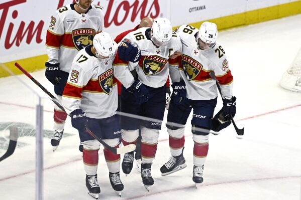 Florida Panthers center Aleksander Barkov (16) is helped off the ice by teammates after crashing into the boards with Ottawa Senators center Tim Stutzle, not shown, during the third period of an NHL hockey game, Thursday, Oct. 10, 2024 in Ottawa, Ontario. (Justin Tang/Canadian Press via AP)