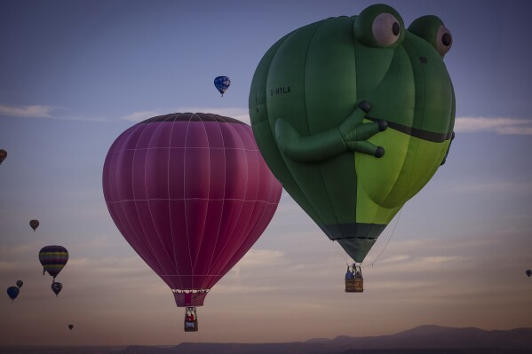 Balloons sail in the sky captured during flight in Meow Wolf's Skyworm hot air balloon during the Albuquerque International Balloon Fiesta at Balloon Fiesta Park in Albuquerque, N.M., on Tuesday, Oct. 8, 2024.v. (Chancey Bush/The Albuquerque Journal via AP)