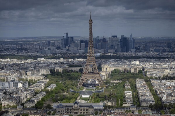 CORRECTS THE YEAR TO 135, NOT 1235 - FILE - Stands are under construction on the Champ-de-Mars in front of the Eiffel Tower, Monday, April 15, 2024 in Paris. La Dame de Fer (The Iron Lady) needs no introduction and is still going strong at 135 years old. Men's and women's volleyball players get to compete at the feet of the 330-meter tower and will be watched by nearly 13,000 fans at the temporary Eiffel Tower Stadium. (AP Photo/Aurelien Morissard, File)