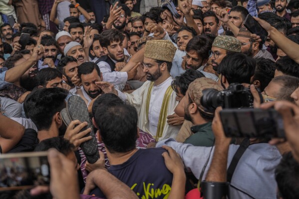 FILE- Supporters assemble to welcome top Kashmiri separatist leader Mirwaiz Umar Farooq, center, as he arrives to offer Friday prayers outside the Jamia Masjid or Grand Mosque in Srinagar, Indian controlled Kashmir, Sept. 22, 2023. (AP Photo/Mukhtar Khan, File)