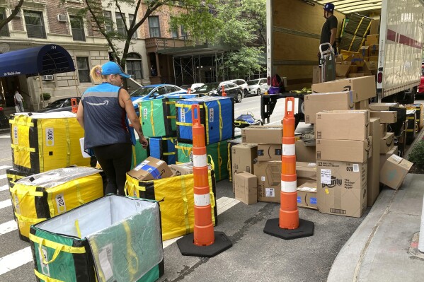 FILE - An Amazon worker sorts deliveries on a street corner on New York's Upper West Side, Aug. 14, 2023. (AP Photo/Richard Drew, File)