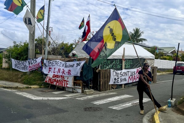 An indigenous Kanak holds the independent flag during the 171th anniversary of France's takeover of the Pacific Archipelago, in Noumea, New Caledonia, French Pacific islands, Tuesday Sept. 24, 2024. (AP Photo/Charlotte Antoine-Perron)