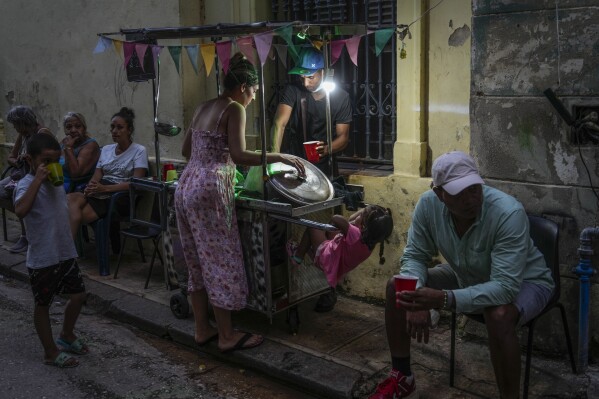 A woman buys soup from a street vendor during a power outage in Havana, Monday, Oct. 21, 2024. (AP Photo/Ramon Espinosa)