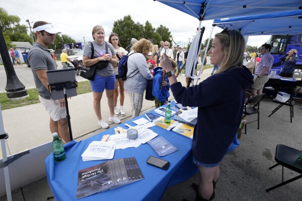 Kristen Eichamer, right, talks to fairgoers in the Project 2025 tent at the Iowa State Fair, Monday, Aug. 14, 2023, in Des Moines, Iowa. With more than a year to go before the 2024 election, a constellation of conservative organizations is preparing for a possible second White House term for Donald Trump. The Project 2025 effort is being led by the Heritage Foundation think tank. (AP Photo/Charlie Neibergall)