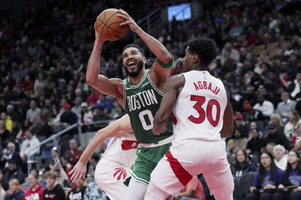 Jayson Tatum (0) de los Celtics de Boston se abre paso entre Ochai Agbaji (30) y Gradey Dick (1) de los Raptors de Toronto, el martes 15 de octubre de 2024. (Nathan Denette/The Canadian Press vía AP)