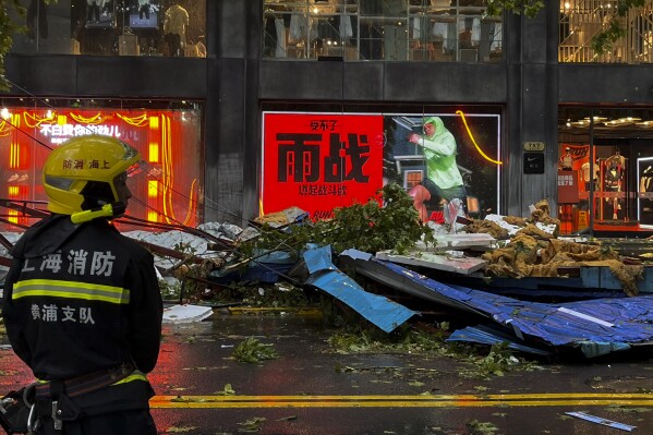 A firefighter stands near debris along a business street in the aftermath of Typhoon Bebinca in Shanghai, China, Monday, Sept. 16, 2024. (Chinatopix Via AP)