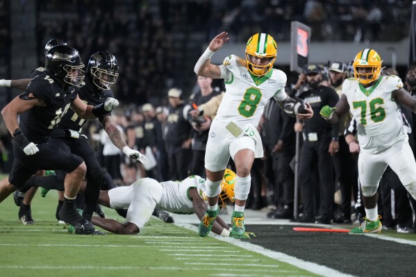 Oregon quarterback Dillon Gabriel (8) tries to stay inbounds while running up the sideline during the second half of an NCAA college football game against Purdue in West Lafayette, Ind., Friday, Oct. 18, 2024. (AP Photo/AJ Mast)