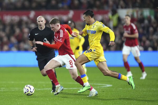 Nottingham Forest's Elliot Anderson and Crystal Palace's Daniel Munoz, right, battle for the ball during the English Premier League soccer match between Nottingham Forest and Crystal Palace at the City Ground, Nottingham, England, Monday Oct. 21, 2024. (Bradley Collyer/PA via AP)