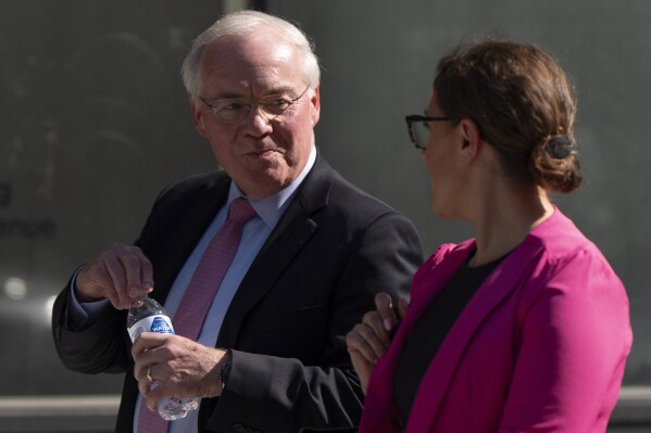 Kroger CEO Rodney McMullen holds a Fred Meyer brand water bottle as he talks with Erin Rolfes, Director of Corporate Communications & Media Relations at Kroger, right, while leaving federal court after testifying during a federal court hearing on Wednesday, Sept. 4, 2024, in Portland, Ore. Fred Meyer's parent company is Kroger. (AP Photo/Jenny Kane)