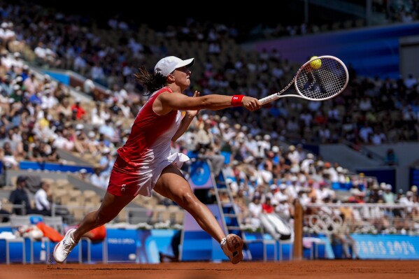 Iga Swiatek of Poland returns the ball against Qinwen Zheng of China during their women's semifinals match at the Roland Garros stadium, at the 2024 Summer Olympics, Thursday, Aug. 1, 2024, in Paris, France. (AP Photo/Manu Fernandez)