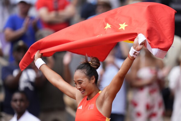 China's Zheng Qinwen holds a Chinese flag after defeating Croatia's Donna Vekic during the Women's Singles tennis final at the Roland Garros stadium at the 2024 Summer Olympics, Saturday, Aug. 3, 2024, in Paris, France. (AP Photo/Manu Fernandez)