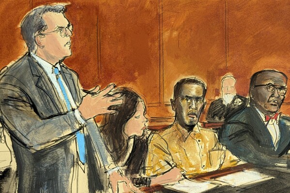 In this courtroom sketch, Sean "Diddy" Combs' defense attorney Marc Agnifilo, left, addresses the judge while Combs, seated second from right, in prison uniform, watches during a hearing in federal court in New York, Thursday, Oct. 10, 2024. Combs' new defense attorney, Anthony Ricco is seated far right. (Elizabeth Williams via AP)