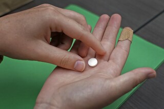 FILE - A patient prepares to take the first of two combination pills, mifepristone, for a medication abortion during a visit to a clinic in Kansas City, Kan., on, Oct. 12, 2022. (AP Photo/Charlie Riedel, File)