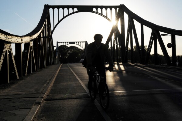 FILE - A cyclist passes over the Glienicke Bridge between Potsdam and Berlin, Germany, on May 6, 2009. They sometimes see those who are part of the swap as they pass each other on an airport tarmac or, as in the Cold War, the Glienicke Bridge connecting West Berlin to Potsdam. In decades of prisoner exchanges, those released have included spies, journalists, drug and arms dealers, and even a well-known athlete. (AP Photo/Sven Kaestner, File)