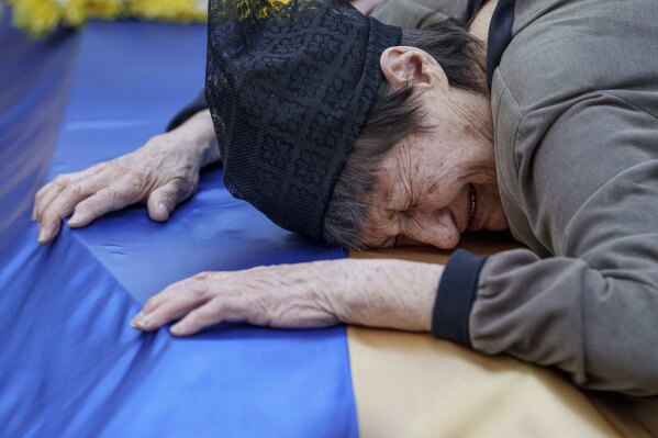 A mother cries near the coffin of her son killed in a Russian rocket attack at a Ukrainian military academy, during his funeral ceremony in Poltava, Ukraine, Saturday Sept. 7, 2024. (AP Photo/Evgeniy Maloletka)