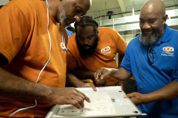 Jackie Robinson, right, an instructor at the Energy Coordinating Agency, a nonprofit focused in part on energy equity, teaches a class at the facility on Tuesday, July 2, 2024, in Philadelphia. (AP Photo/Joe Lamberti)