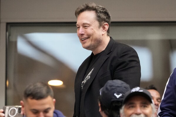 Elon Musk talks to other spectators while watching play between Jannik Sinner, of Italy, and Taylor Fritz, of the United States, during the men's singles final of the U.S. Open tennis championships, Sunday, Sept. 8, 2024, in New York. (AP Photo/Kirsty Wigglesworth)