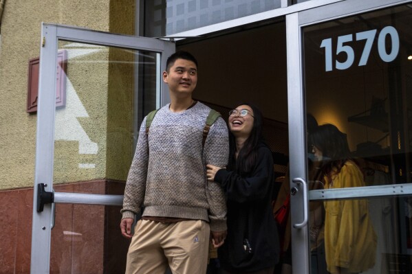 Shoppers emerge from a store, Tuesday, March 14, 2023, in Las Vegas. (AP Photo/Ty O'Neil)