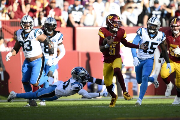 Washington Commanders quarterback Jayden Daniels (5) runs from Carolina Panthers safety Nick Scott (21) and linebacker Marquis Haynes Sr. (45) during the first half of an NFL football game, Sunday, Oct. 20, 2024, in Landover, Md. (AP Photo/Nick Wass)