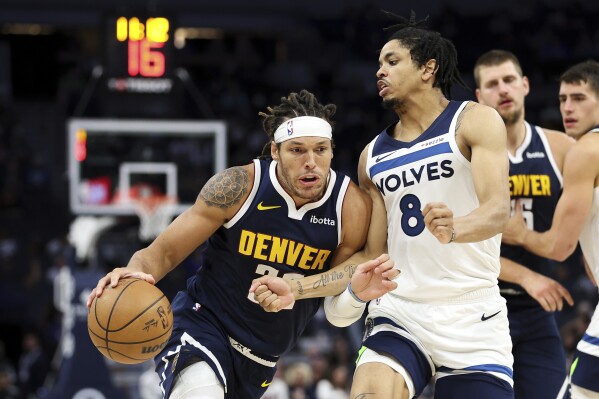 Denver Nuggets forward Aaron Gordon, left, drives past Minnesota Timberwolves forward Josh Minott (8) during the second half of a preseason NBA basketball game, Thursday, Oct. 17, 2024, in Minneapolis. (AP Photo/Matt Krohn)