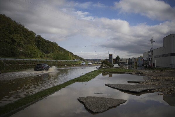 A car drives in a flooded street near a shopping mall in Givors, central France, after torrential rains and flooding submerged roads and railways, Friday, Oct. 18, 2024. (AP Photo/Laurent Cirpiani)