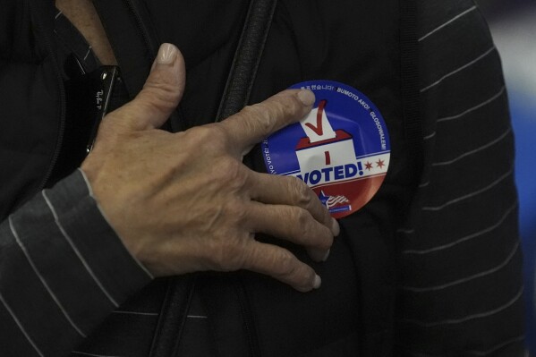 A person attaches a "I Voted" sticker to their shirt on the first day of early voting for the 2024 Presidential General Election Thursday, Oct. 3, 2024, in Chicago. (AP Photo/Charles Rex Arbogast)