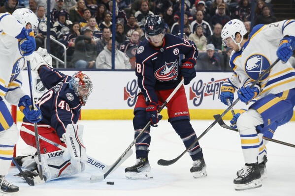 Columbus Blue Jackets' Daniil Tarasov, left, makes a save as teammate Damon Severson, center, and Buffalo Sabres' Dylan Cozens look for a rebound during the first period of an NHL hockey game Thursday, Oct. 17, 2024, in Columbus, Ohio. (AP Photo/Jay LaPrete)