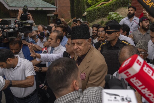 National Conference party leader Farooq Abdullah, center, wearing black cap, is surrounded by journalists as party celebrate early leads in the election for a local government in Indian controlled Kashmir, Srinagar, Tuesday, Oct. 8, 2024. (AP Photo/Dar Yasin)