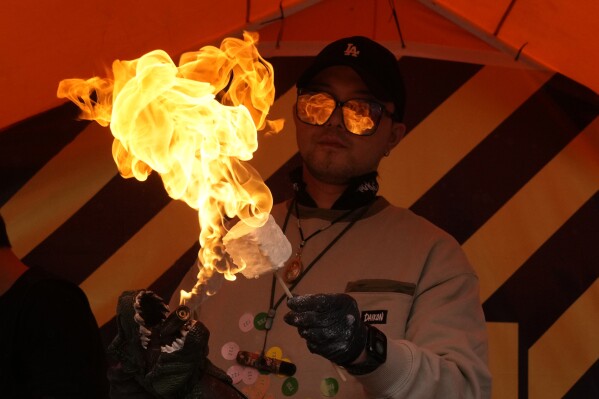 A vendor makes flaming marshmallow ice cream at a food stall in Beijing, Friday, Oct. 18, 2024. (AP Photo/Ng Han Guan)