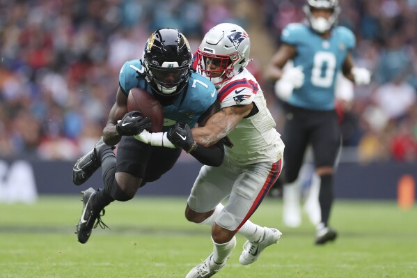 Jacksonville Jaguars wide receiver Brian Thomas Jr. (7) is tackled by New England Patriots cornerback Christian Gonzalez (0) during the first half of an NFL football game, Sunday, Oct. 20, 2024, in London. (AP Photo/Ian Walton)