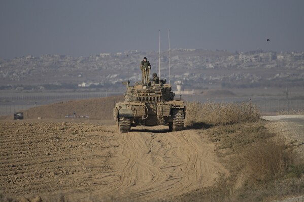 Israeli Defense Forces soldiers work on their tank near the Israel-Gaza border, as seen from southern Israel, Wednesday, Oct. 16, 2024. (AP Photo/Tsafrir Abayov)