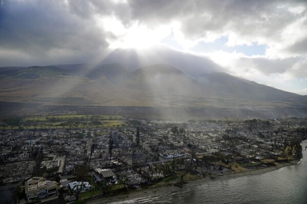 Sunlight bursts through a cloud over the wreckage of a wildfire in Lahaina, Hawaii, Aug. 10, 2023. (AP Photo/Rick Bowmer)