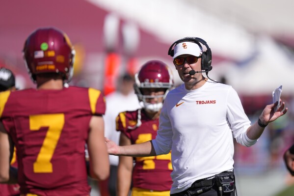 Southern California head coach Lincoln Riley, right, talks with quarterback Miller Moss during the second half of an NCAA college football game against Wisconsin, Saturday, Sept. 28, 2024, in Los Angeles. (AP Photo/Mark J. Terrill)