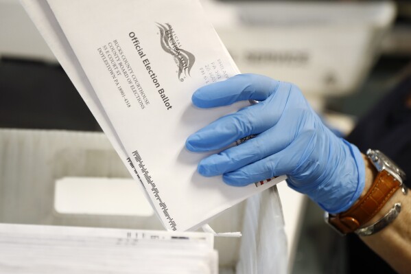 FILE - A worker processes mail-in ballots at the Bucks County Board of Elections office prior to the primary election in Doylestown, Pa., May 27, 2020. (AP Photo/Matt Slocum, File)