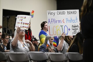 FILE - Parents, students, and staff of Chino Valley Unified School District hold up signs in favor of protecting LGBTQ+ policies at Don Antonio Lugo High School, in Chino, Calif., June 15, 2023. California Gov. Gavin Newsom signed a law Monday, July 15, 2024, barring school districts from passing policies that require schools to notify parents if their child asks to change their gender identification. (Anjali Sharif-Paul/The Orange County Register via AP, File)