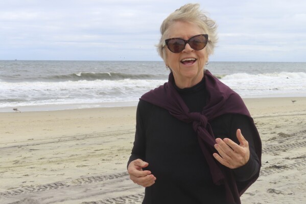 Kimberly Paterson, a leader of a group opposed to a project to bring an offshore wind power cable onshore in her community, speaks, Sept. 30, 2024, on a beach in Sea Girt, N.J., where the cable is projected to come ashore. (AP Photo/Wayne Parry)