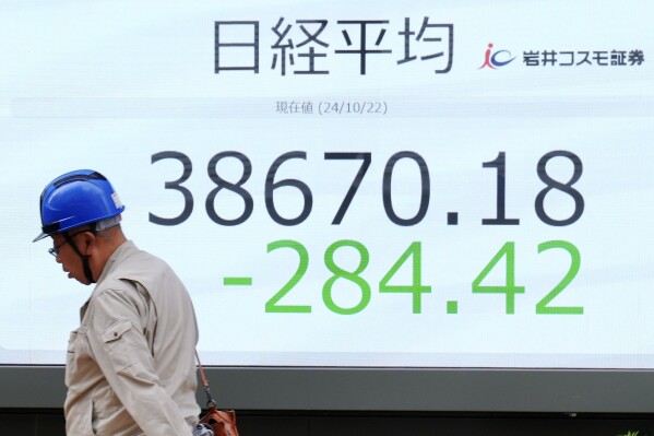 A person walks in front of an electronic stock board showing Japan's Nikkei index at a securities firm Tuesday, Oct. 22, 2024, in Tokyo. (AP Photo/Eugene Hoshiko)