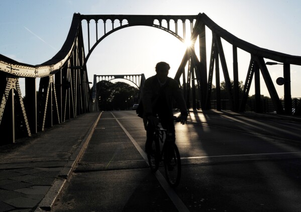 FILE - A cyclist passes over the Glienicke Bridge between Potsdam and Berlin, Germany, on May 6, 2009. They sometimes see those who are part of the swap as they pass each other on an airport tarmac or, as in the Cold War, the Glienicke Bridge connecting West Berlin to Potsdam. In decades of prisoner exchanges, those released have included spies, journalists, drug and arms dealers, and even a well-known athlete. (AP Photo/Sven Kaestner, File)