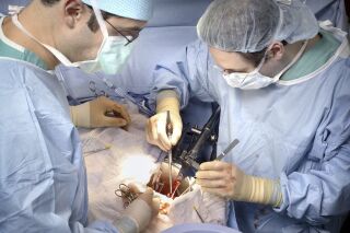 In this photo provided by Johns Hopkins Medicine, Dr. Dorry Segev, right, performs the first U.S. transplant of a kidney from a deceased donor who had HIV into a recipient living with HIV, in Baltimore, in March 2016. (Johns Hopkins Medicine via AP)