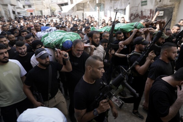 Mourners march during a funeral with the bodies of Palestinians Ahmed Abu Arra from the town of Aqaba, left, and Raafat Dawasa from the town of Silat Al-Harithiya, both draped in the Hamas flag and killed in an Israeli strike in the Jenin refugee camp, in the West Bank city of Jenin, Sunday, Aug. 18, 2024. Israel's military said Saturday it struck a "terrorist cell" in Jenin. The Palestinian health ministry there said two bodies were taken to a government hospital; Hamas claimed the two men as commanders in its military wing.(AP Photo/Majdi Mohammed)