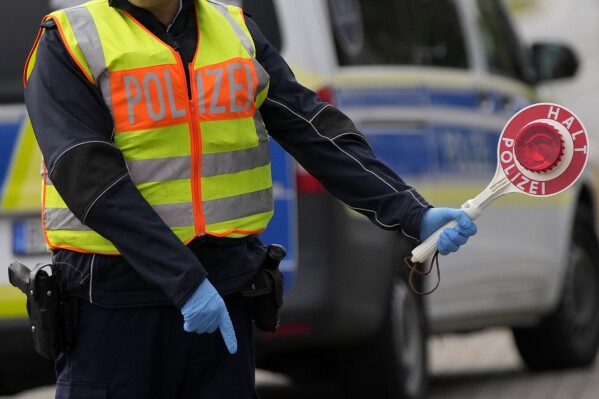 FILE - A German federal police officer stops cars and trucks at a border crossing point between Germany and Czech Republic in Furth am Wald, Germany, Tuesday, Oct. 10, 2023. (AP Photo/Matthias Schrader, File)