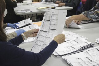 FILE— An election worker examines a ballot at the Clackamas County Elections office on May 19, 2022, Oregon City, Ore. (AP Photo/Gillian Flaccus, File)