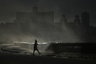 Una persona pesca en el muelle mientras las olas rompen durante un apagón en La Habana, el lunes 21 de octubre de 2024. (AP Foto/Ramón Espinosa)