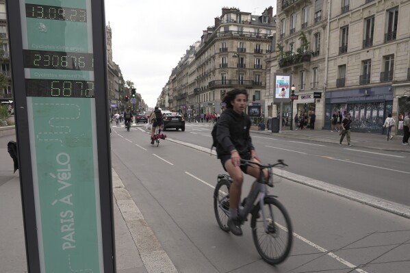 - FILE - A man rides past a bicycle counter in Paris, Wednesday, Sept. 13, 2023. (AP Photo/John Leicester, File)