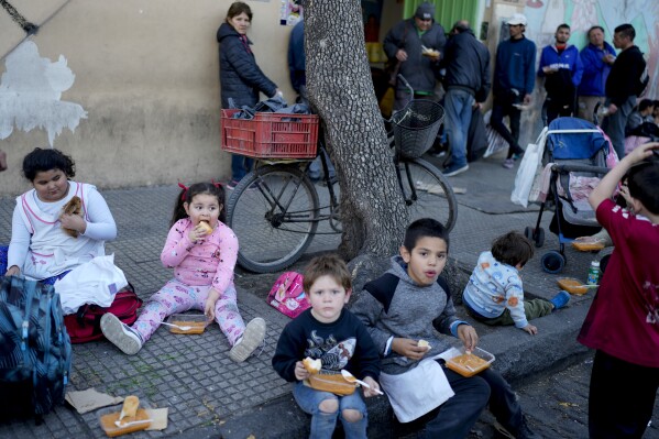 Children eat a free, cooked meal outside a soup kitchen on the outskirts of Buenos Aires, Argentina, Thursday, Sept. 12, 2024. (AP Photo/Natacha Pisarenko)