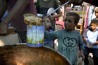 A displaced child lines up for food distribution in Deir al-Balah, Gaza Strip, Thursday, Oct. 17, 2024. (AP Photo/Abdel Kareem Hana)