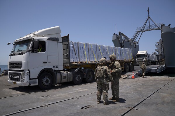 FILE - U.S. Army soldiers stand next to trucks arriving loaded with humanitarian aid at the U.S.-built floating pier Trident before reaching the beach on the coast of the Gaza Strip, June 25, 2024. (AP Photo/Leo Correa, File)