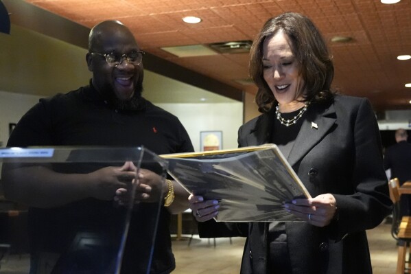 Ishmael Trainor, owner of Legenderie Records and Coffee House, left, shows Democratic presidential nominee Vice President Kamala Harris a Marvin Gaye record during a campaign stop at the Black-owned small business, Monday, Oct. 14, 2024, in Erie, Pa. (AP Photo/Jacquelyn Martin)