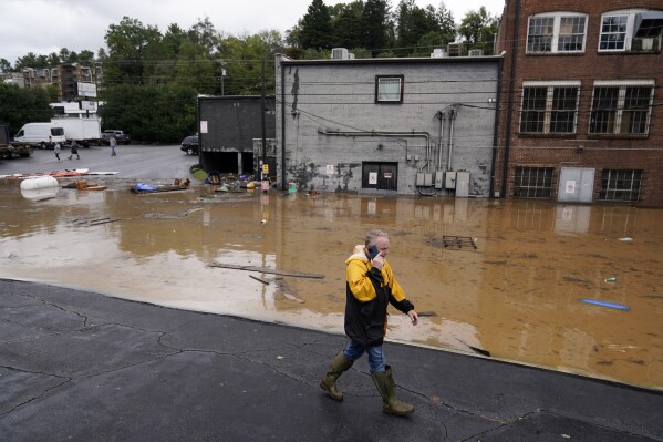 FILE - A man walks near a flooded area near the Swannanoa river, effects from Hurricane Helene , Friday, Sept. 27, 2024, in Asheville, N.C. (AP Photo/Erik Verduzco, File)