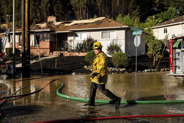 Un bombero pasa junto a una casa calcinada por el incendio de Keller cerca de la carretera Interestatal 580 en Oakland, California, el viernes 18 de octubre de 2024. (Foto AP/Noah Berger)